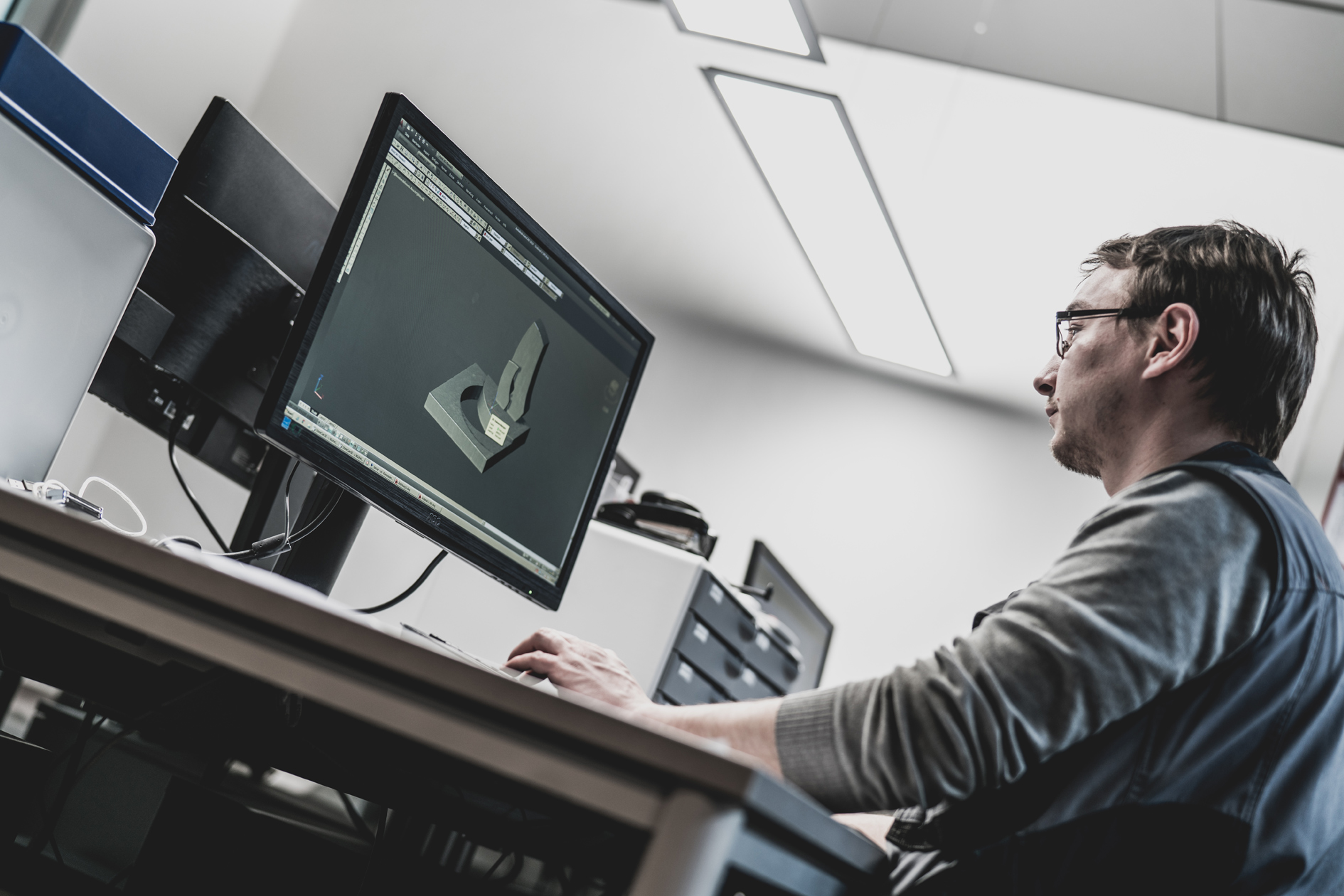 Ein Mann arbeitet am Schreibtisch an einem 3D-Modell einer Grabanlage